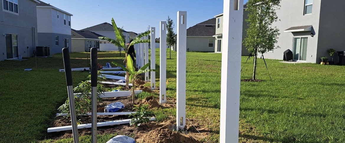 Vinyl fence posts set in concrete on a Florida job site