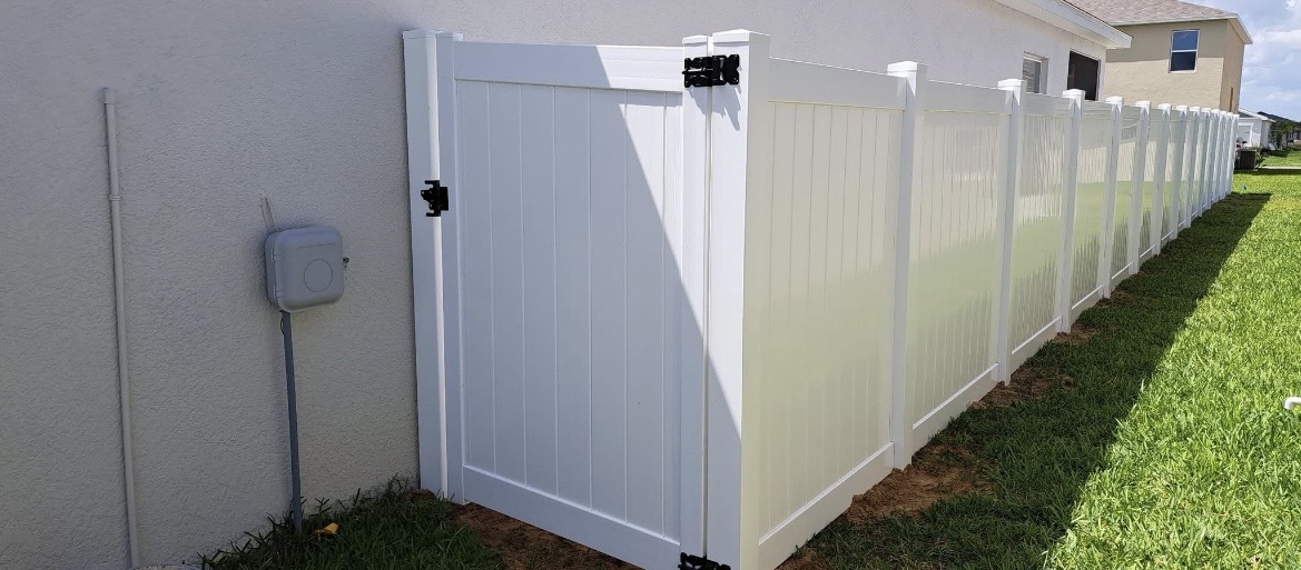 White vinyl privacy fence with single-swing gate